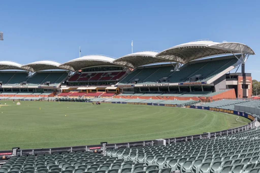 Empty green seats curving around the oval's lush field, white canopy roofs over the eastern grandstands and a cloudless sky.